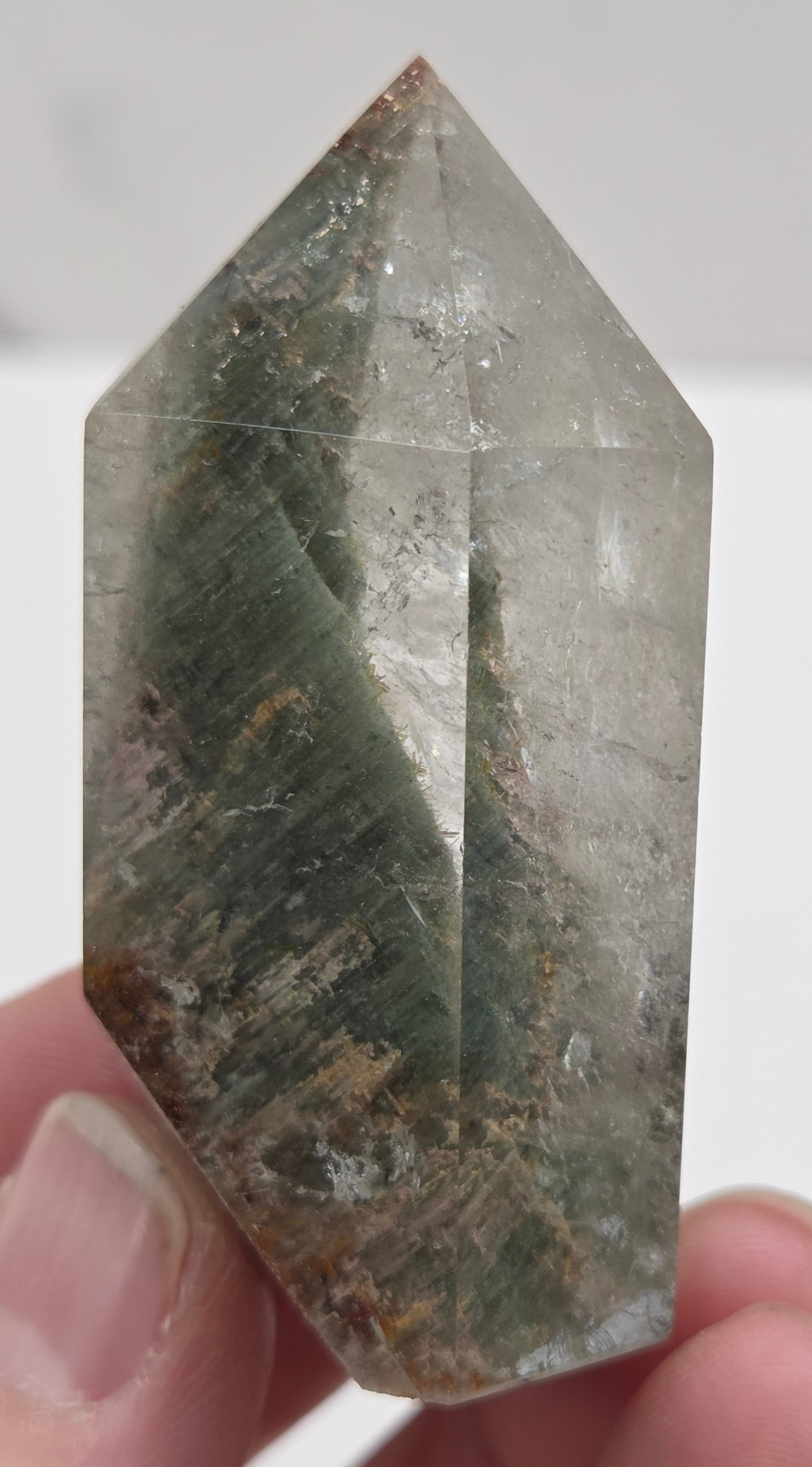 Hand holding a Garden Quartz crystal with a white background