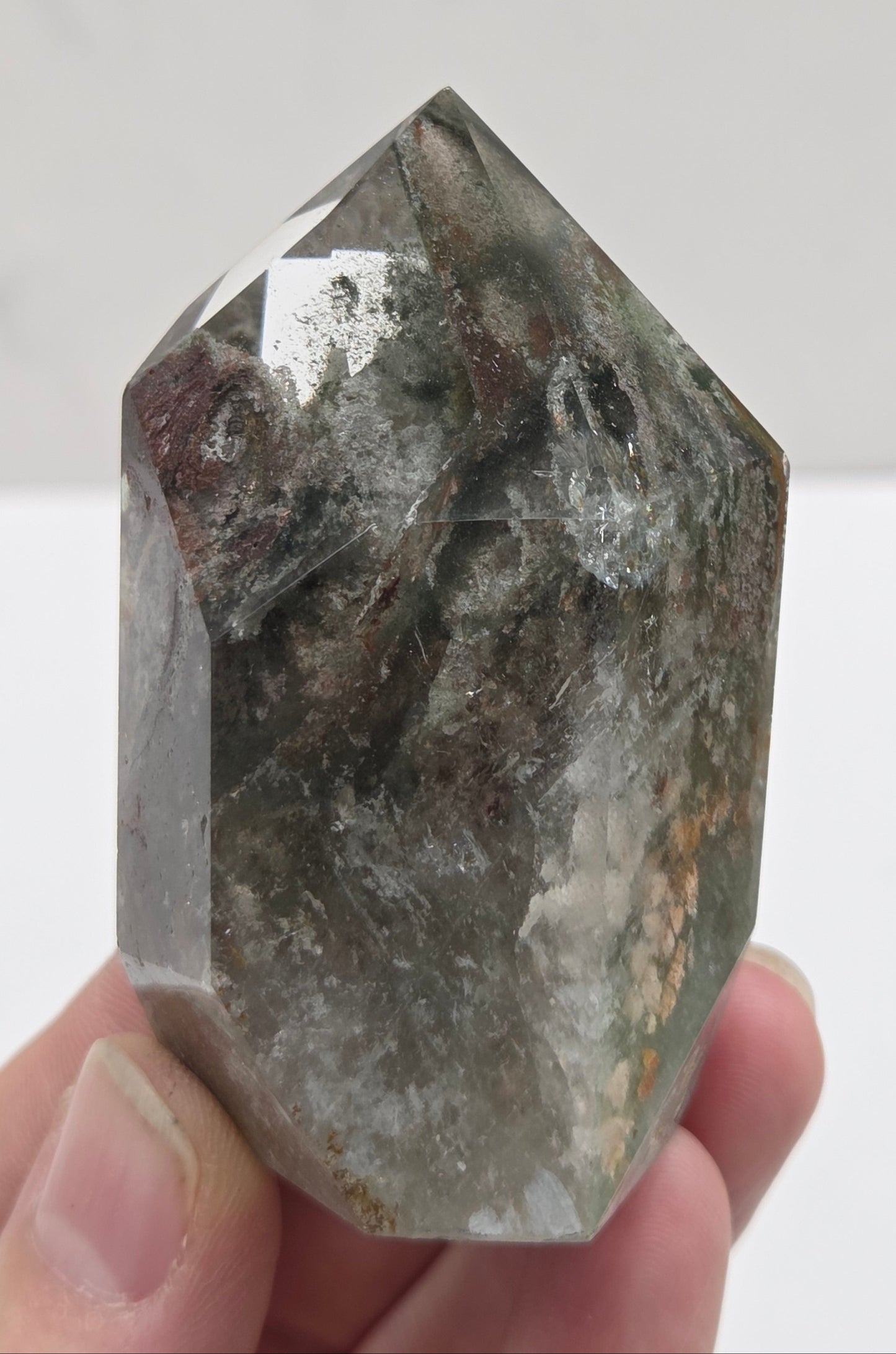 Garden Quartz crystal held by a hand against a white background