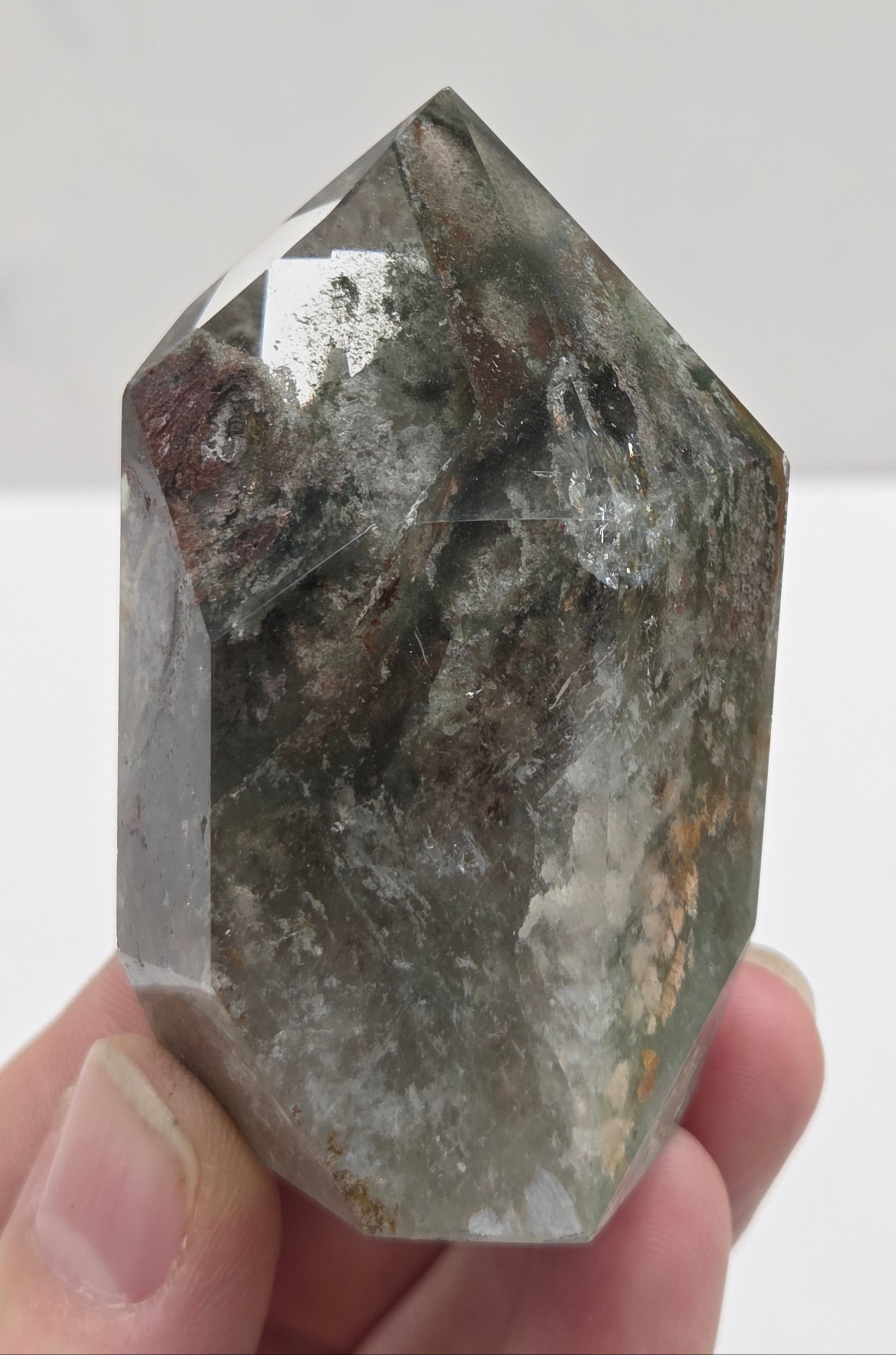 Garden Quartz crystal held by a hand against a white background
