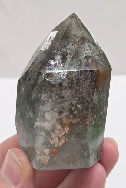 Person holding a Garden Quartz crystal with a white background
