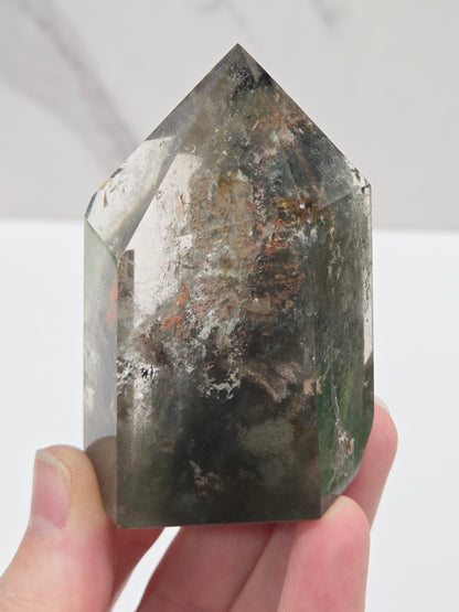Hand holding a Garden Quartz crystal with a white background