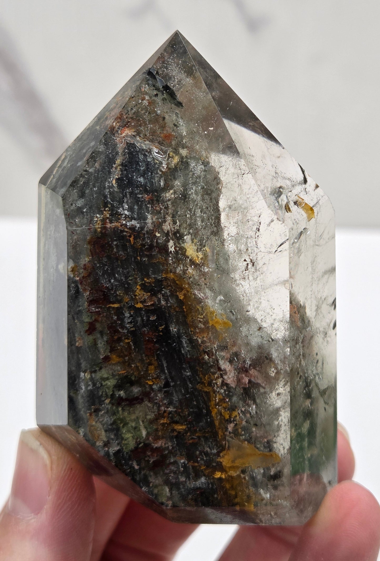 Hand holding a Garden Quartz crystal with a white background