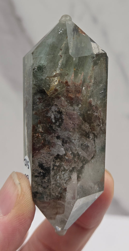 Garden Quartz Crystal held by a hand with a neutral background