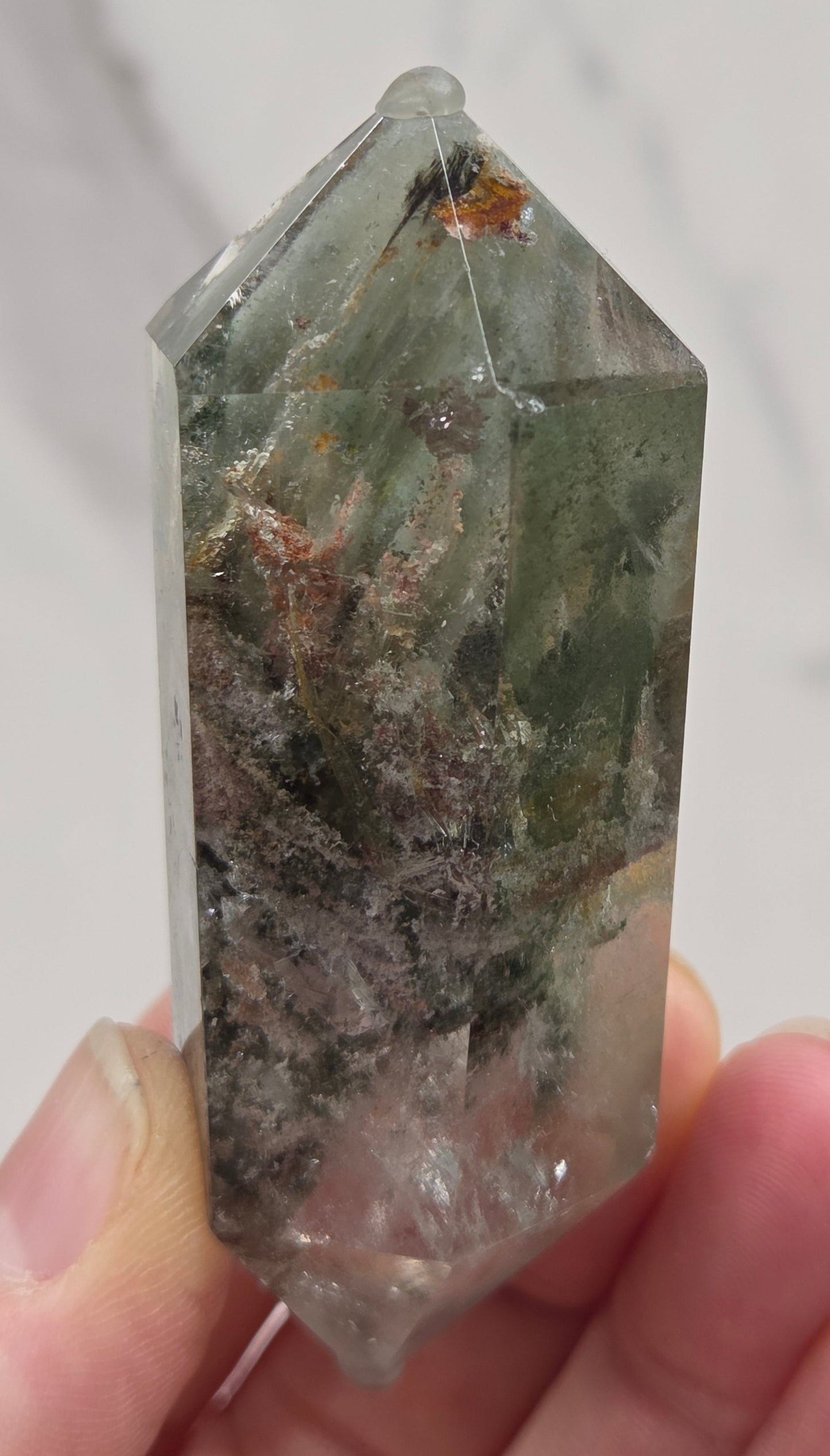Garden Quartz Crystal held by a hand with a neutral background
