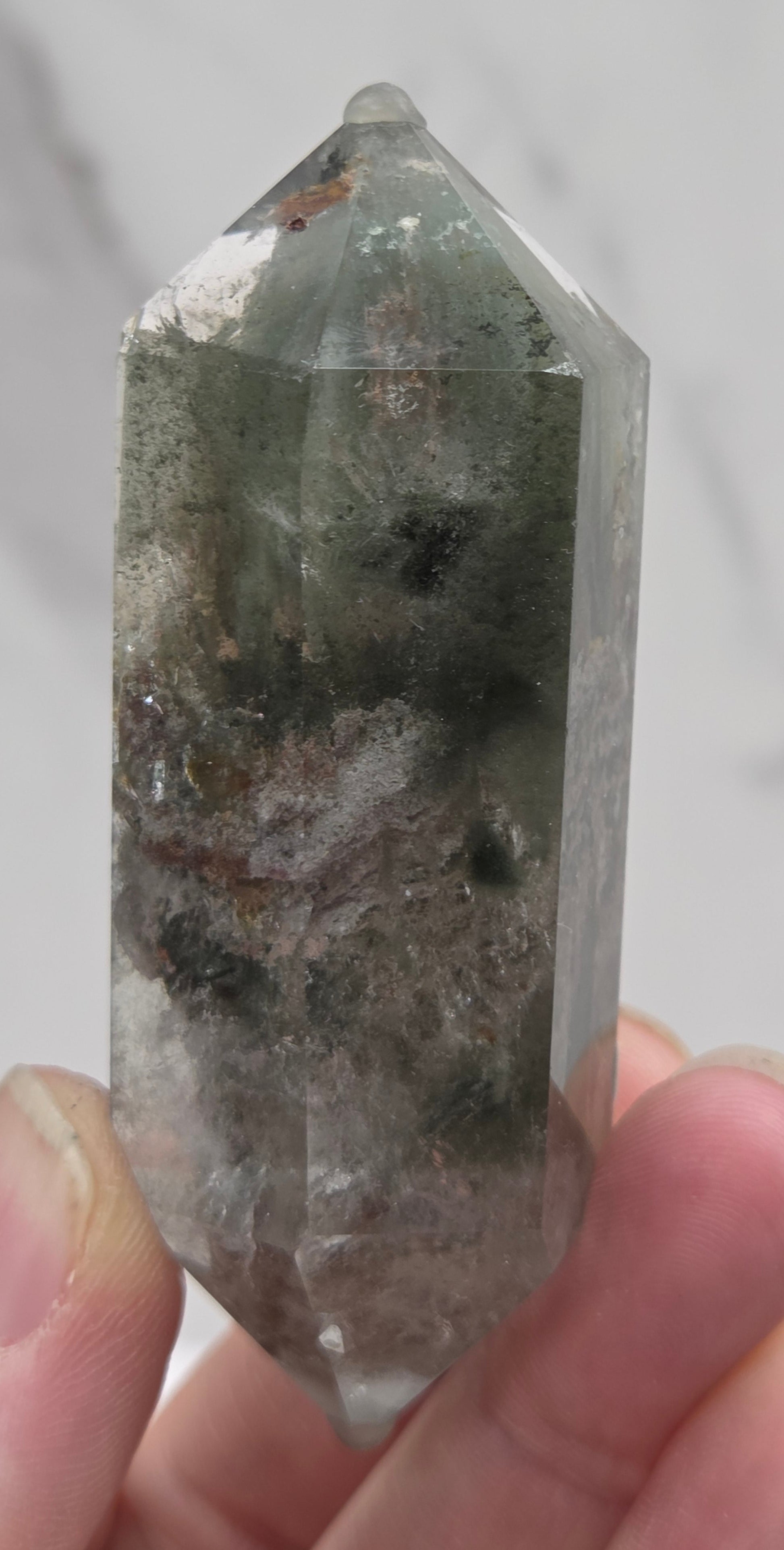Garden Quartz Crystal held by a hand with a neutral background