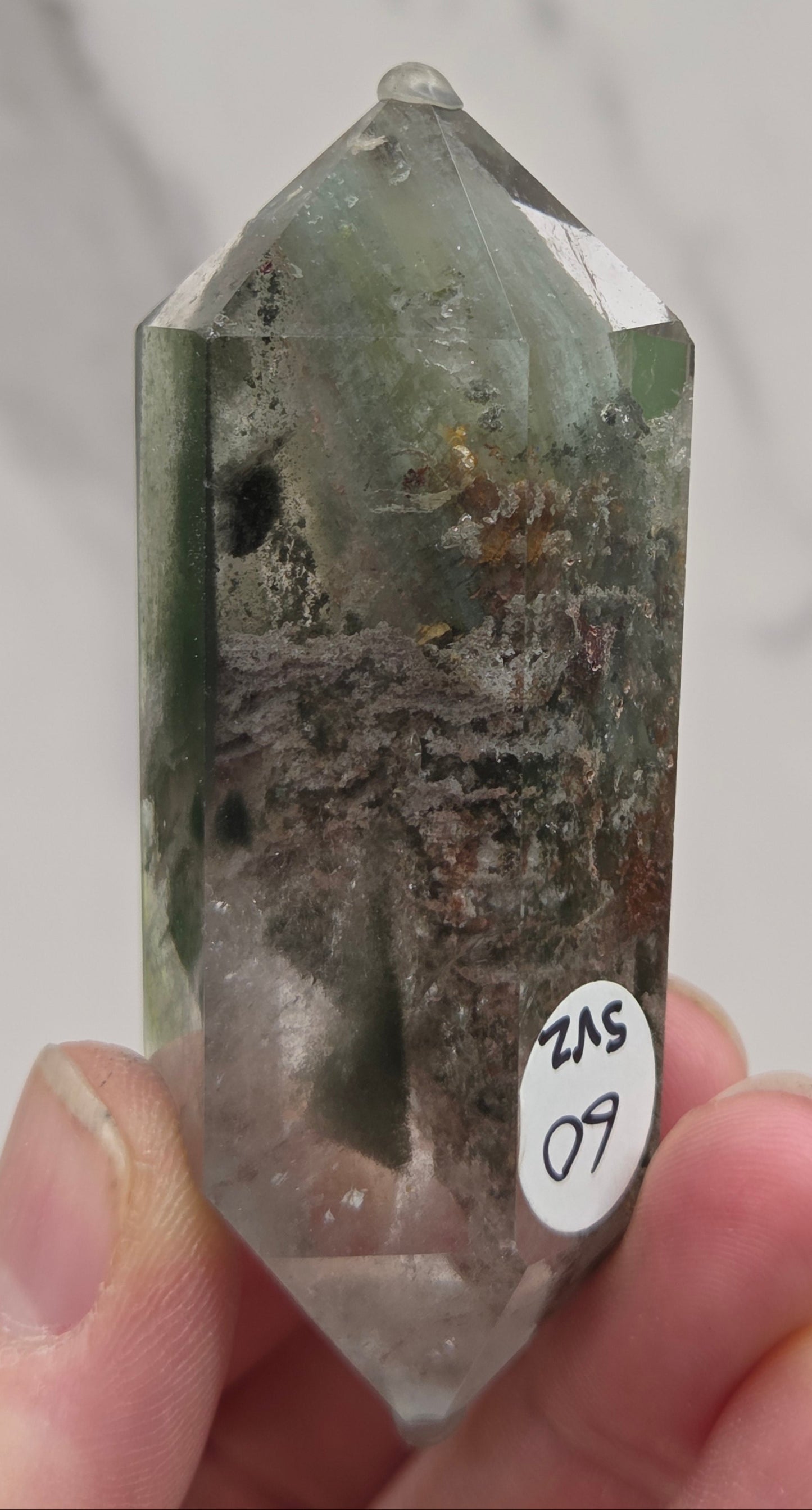 Garden Quartz Crystal held by a hand with a neutral background