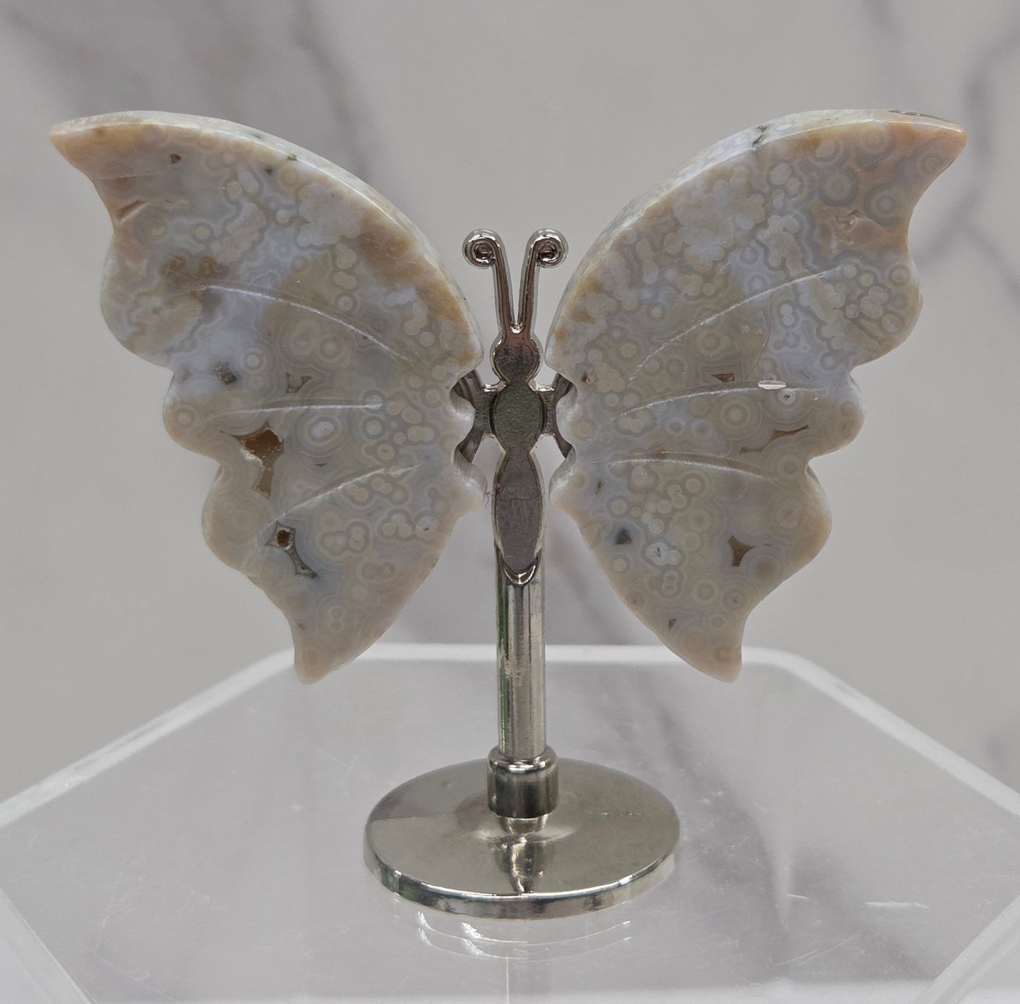 Butterfly-shaped jasper wings on stands with a marble-like texture against a neutral background