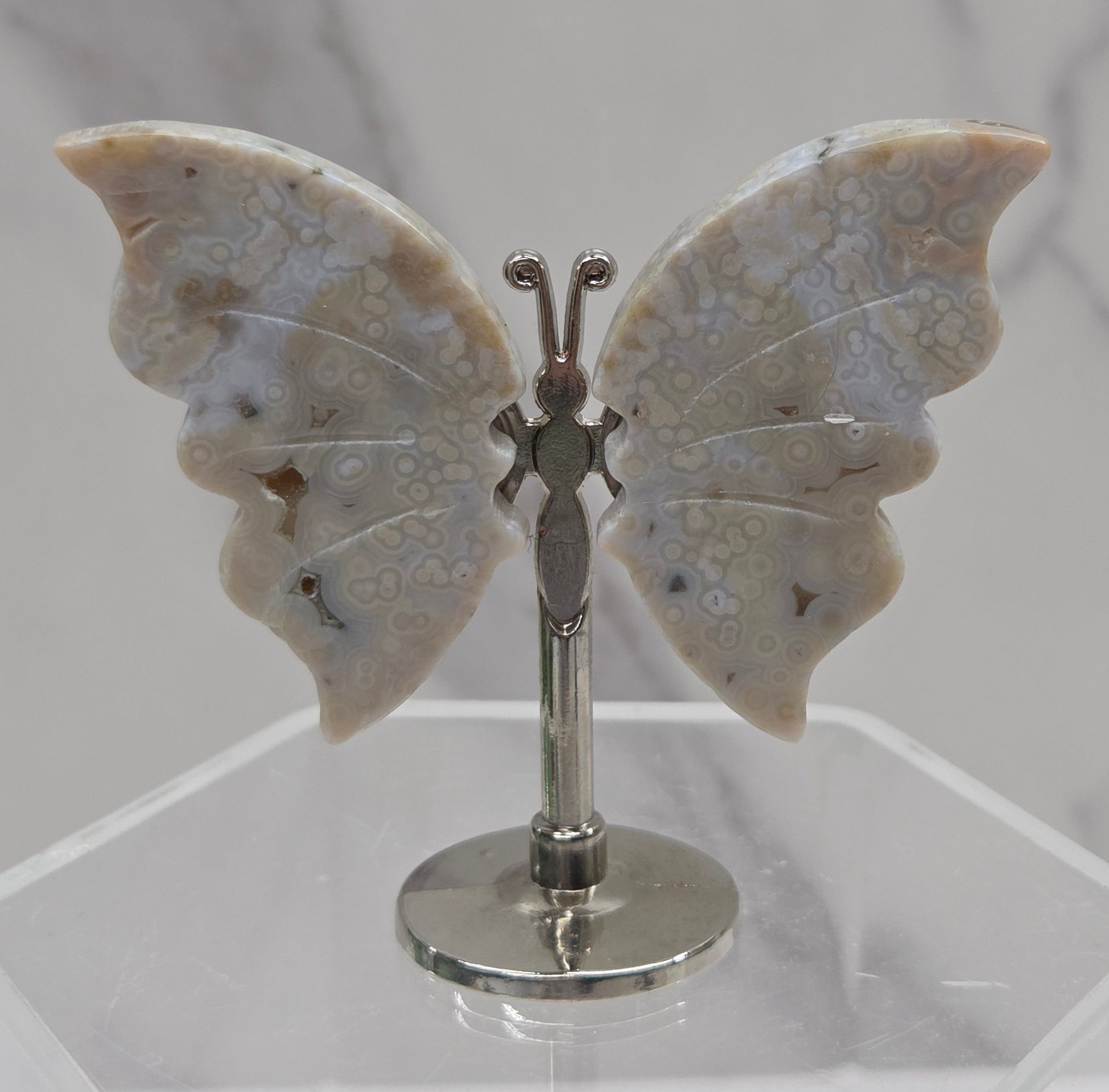 Butterfly-shaped jasper wings on stands with a marble-like texture against a neutral background