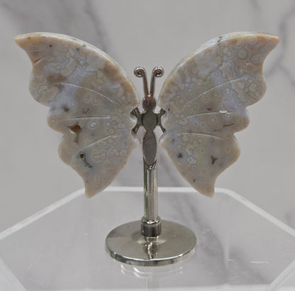 Butterfly-shaped jasper wings on stands with a marble-like texture against a neutral background