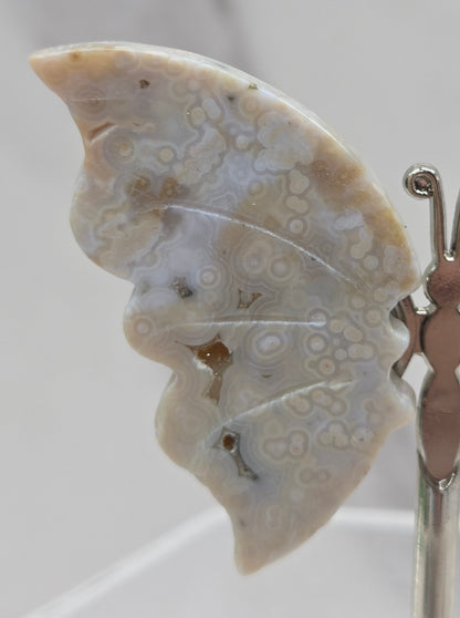 Butterfly-shaped jasper wings on stands with a marble-like texture against a neutral background