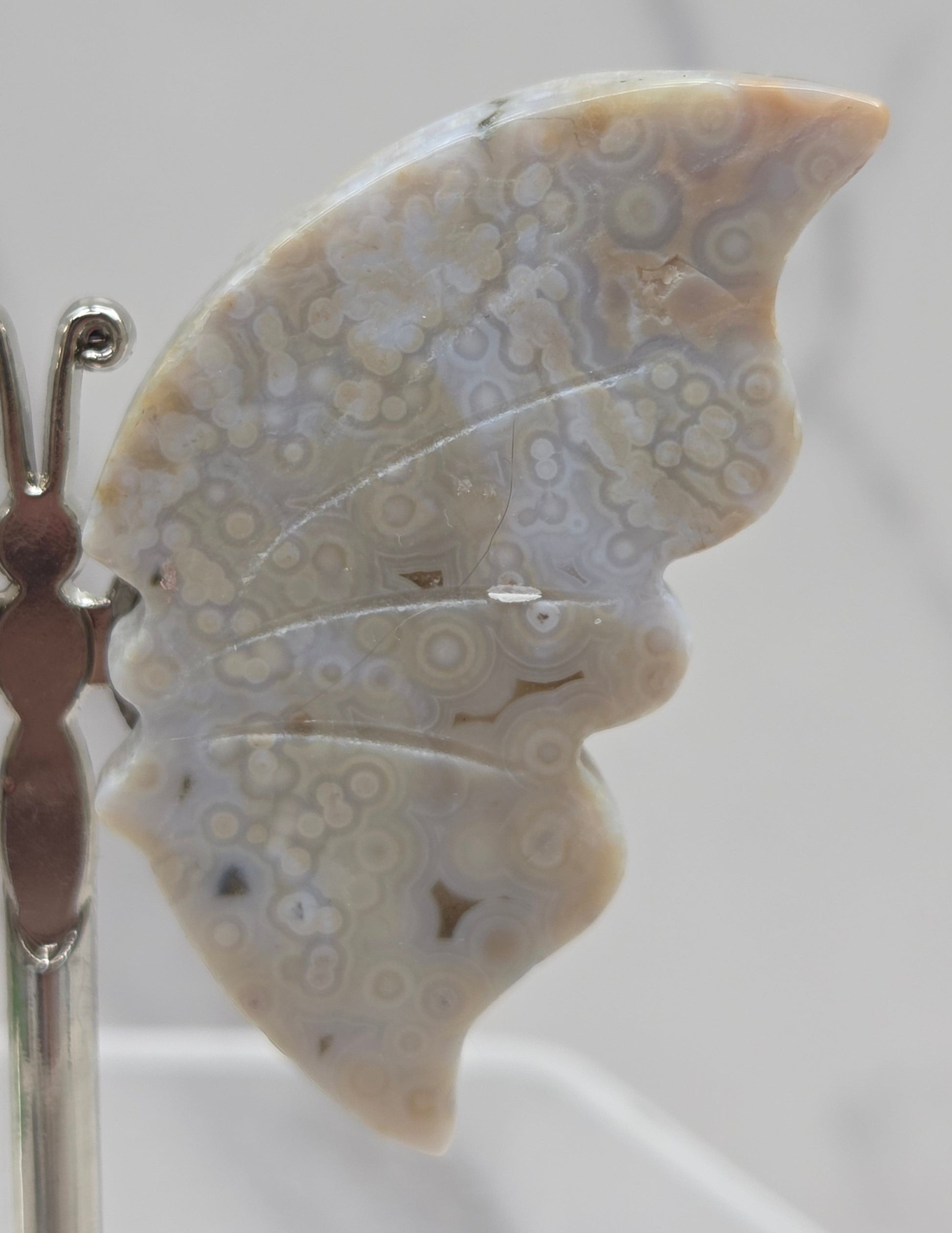 Butterfly-shaped jasper wings on stands with a marble-like texture against a neutral background
