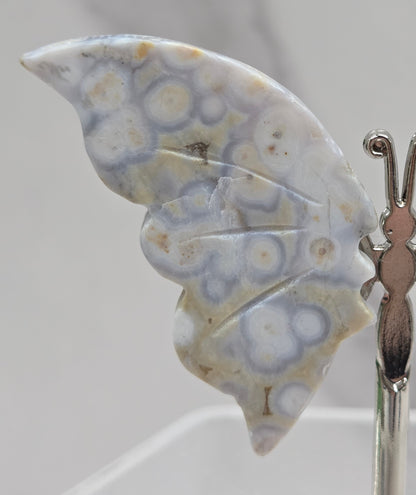 Butterfly-shaped jasper wings on stands with a marble-like texture against a neutral background