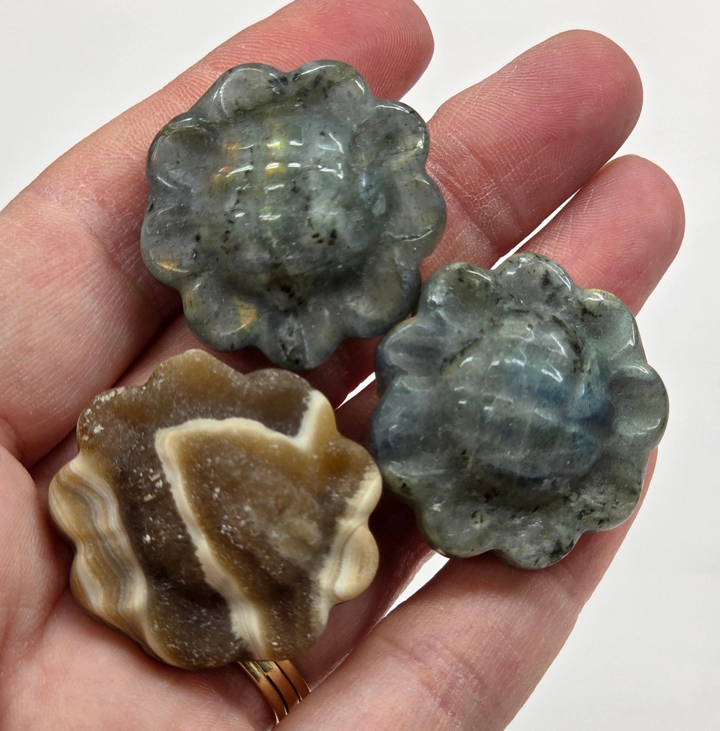 Three sunflower shaped crystal carvings held in a hand against a white background