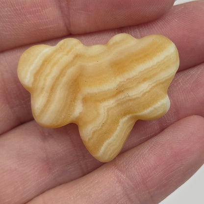 Orange Calcite butterfly carving held in a hand against a white background