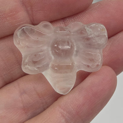 Clear Quartz butterfly carving held in a hand against a white background