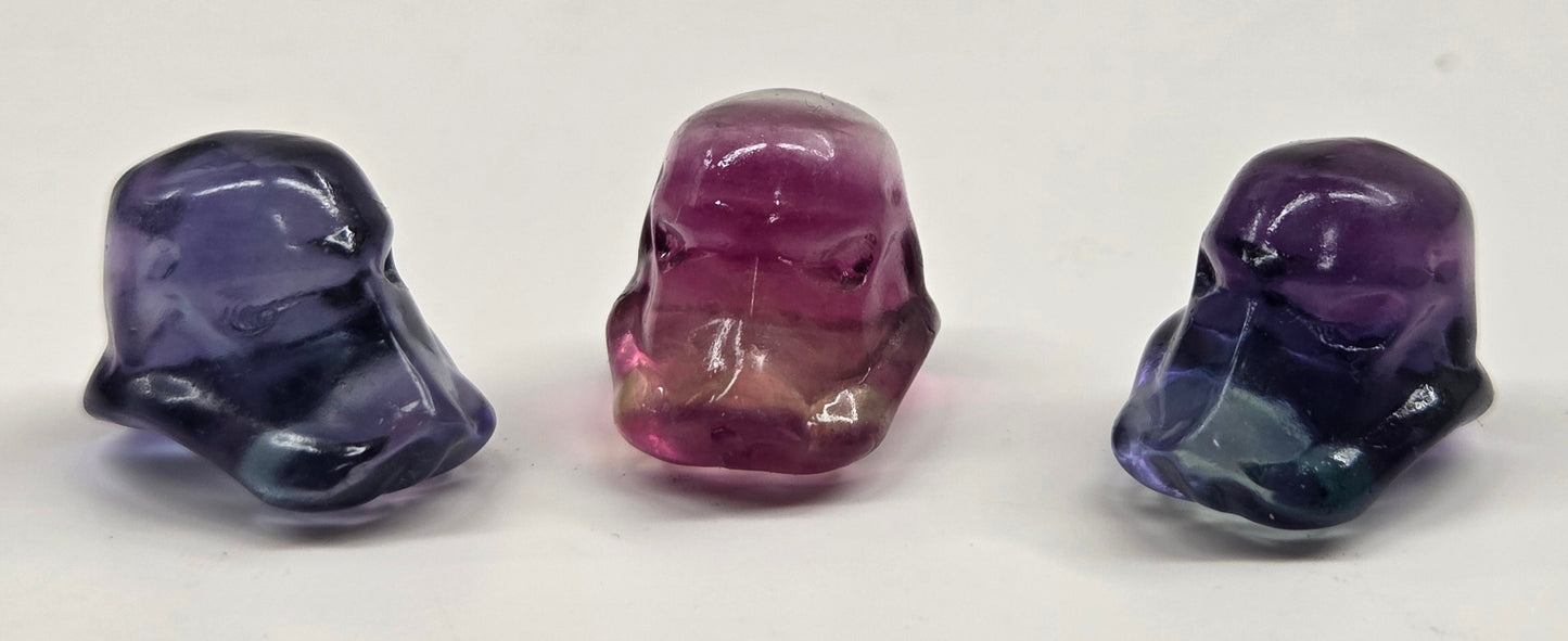 3 mini fluorite carvings of storm trooper helmets on a white background