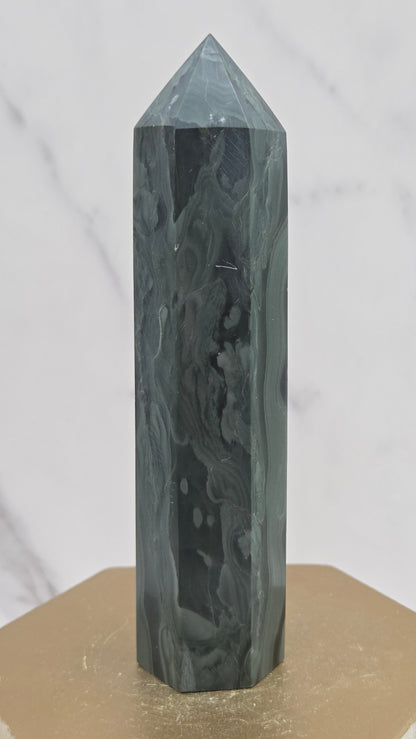Green wave picture jasper tower on a wood base on a white background