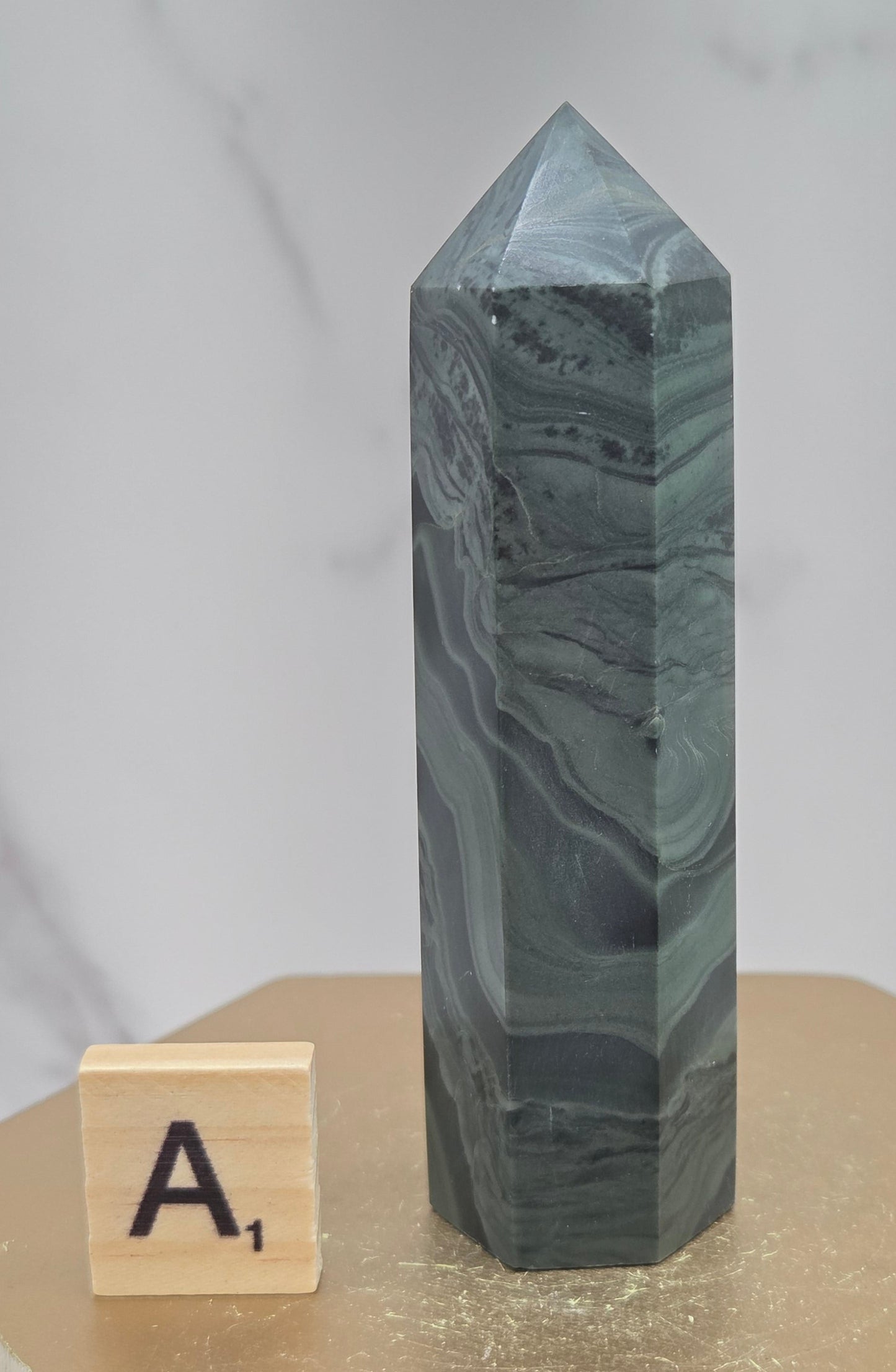 Green wave picture jasper tower on a wood base on a white background
