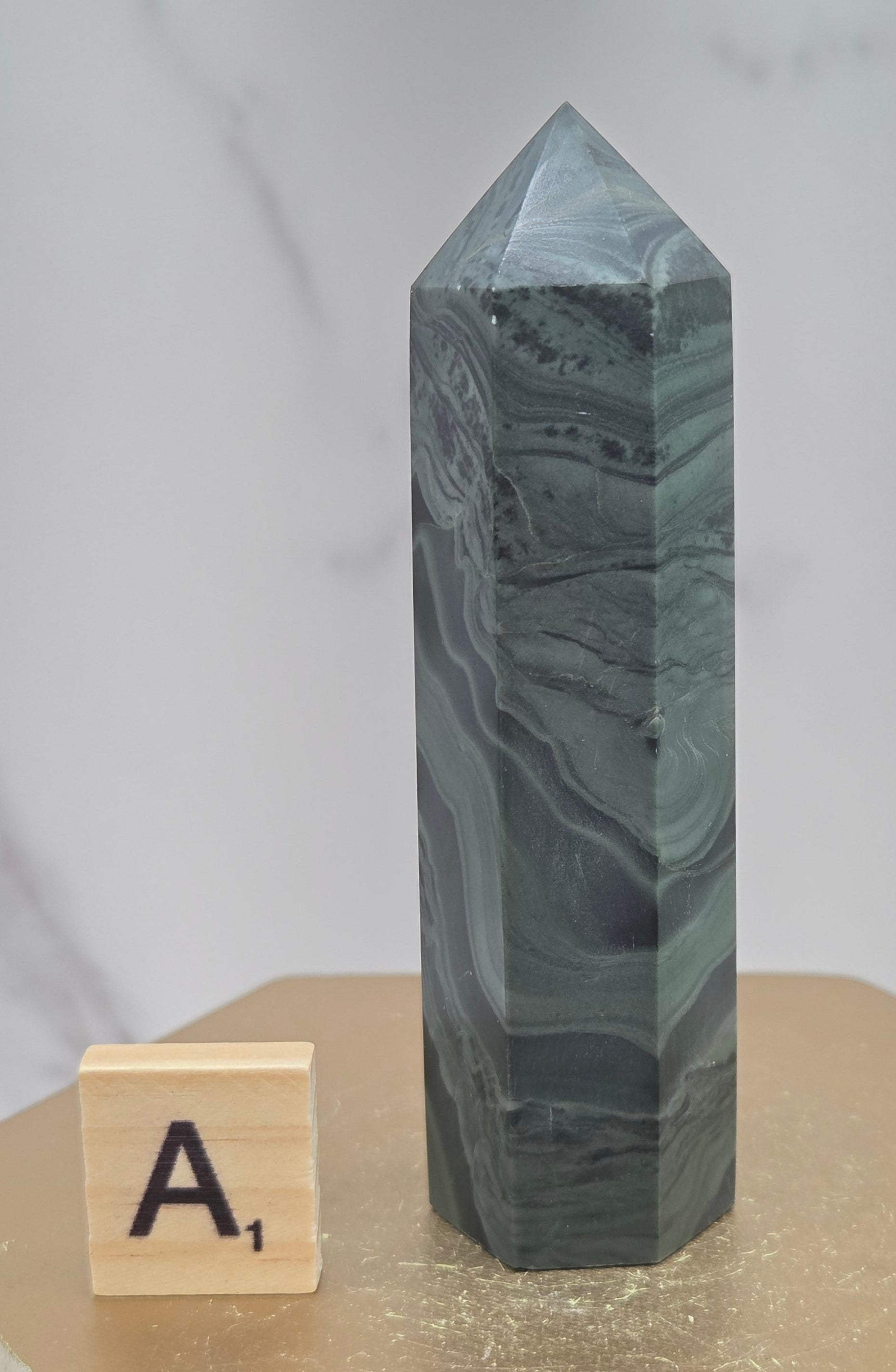 Green wave picture jasper tower on a wood base on a white background
