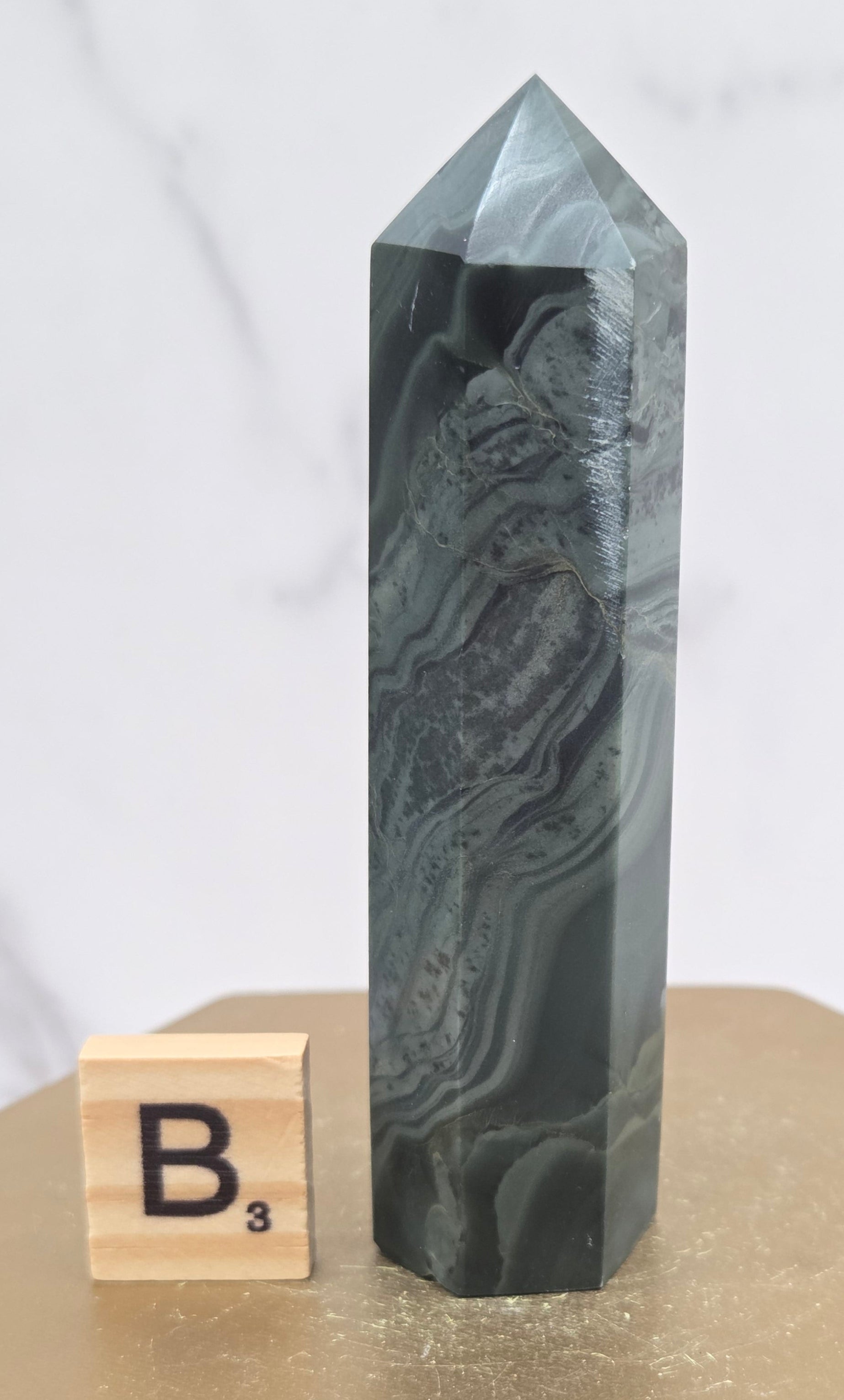 Green wave picture jasper tower on a wood base on a white background