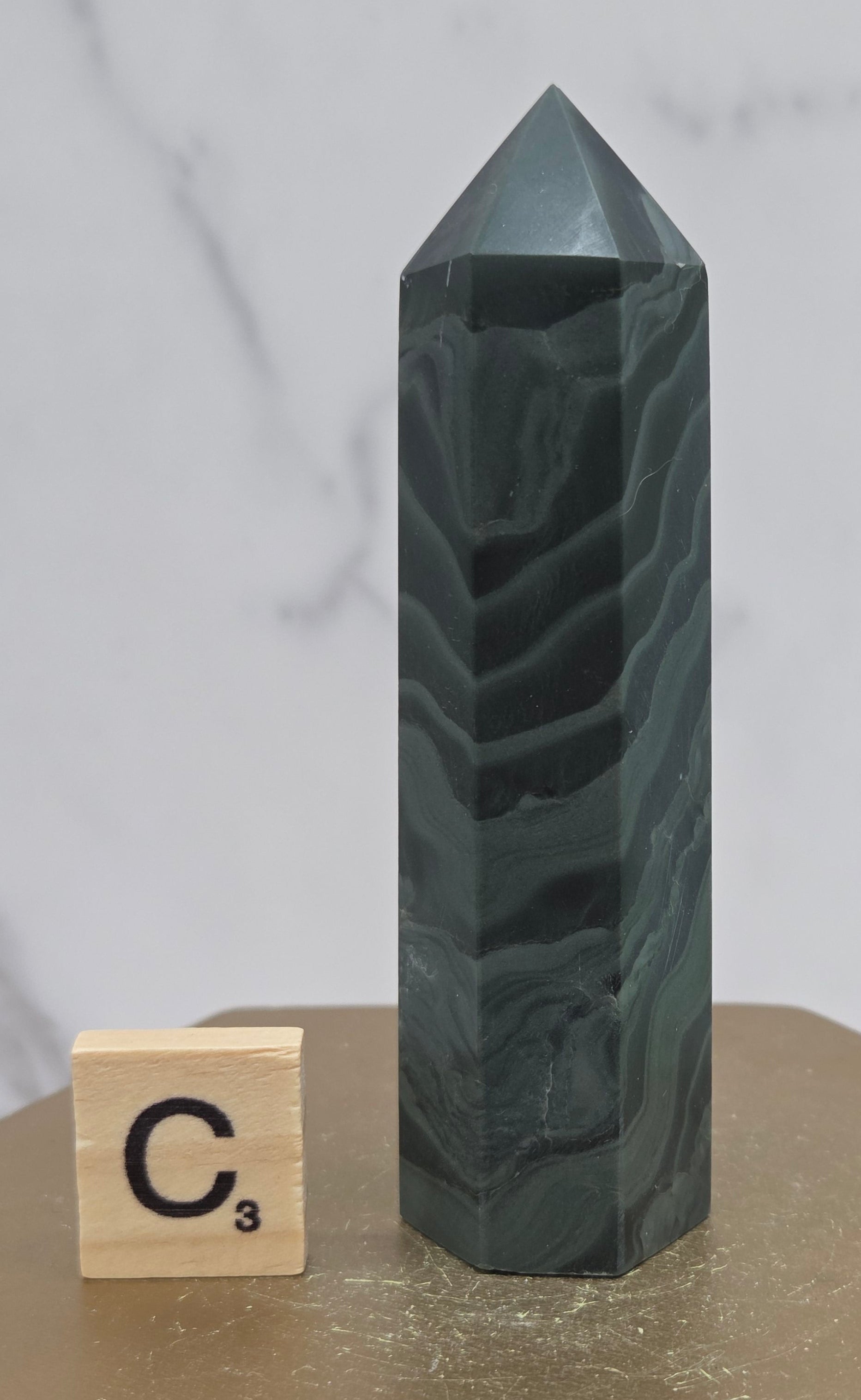 Green wave picture jasper tower on a wood base on a white background