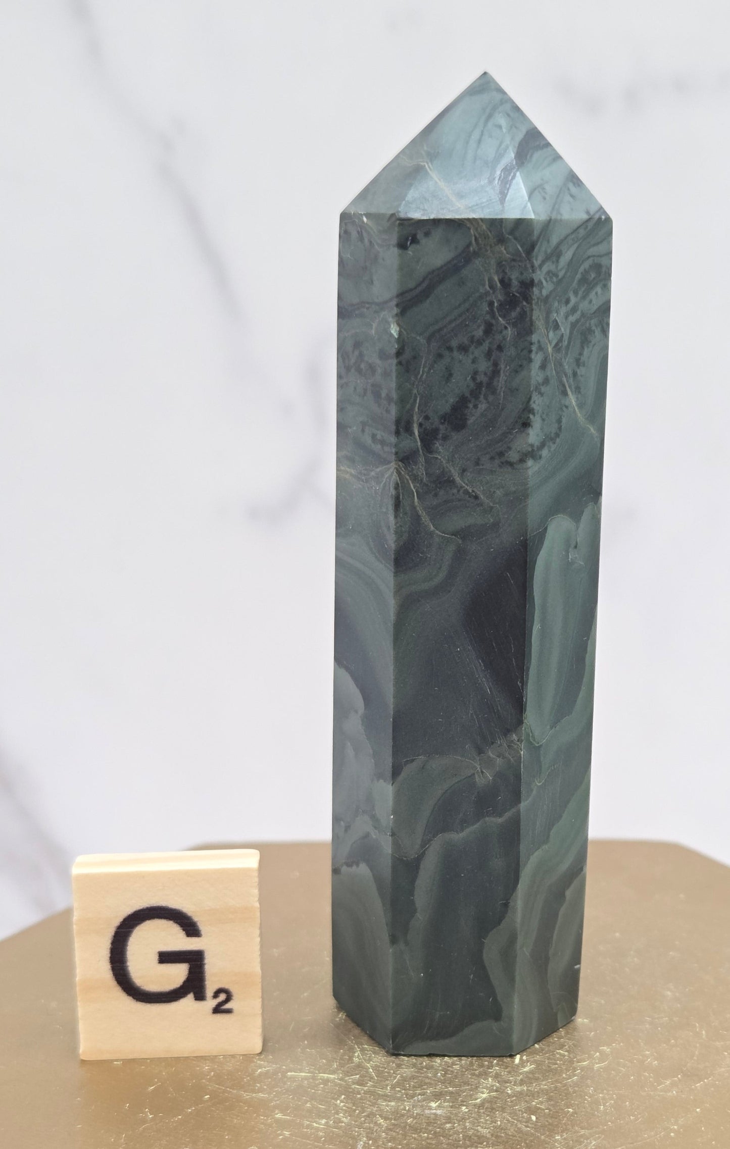Green wave picture jasper tower on a wood base on a white background
