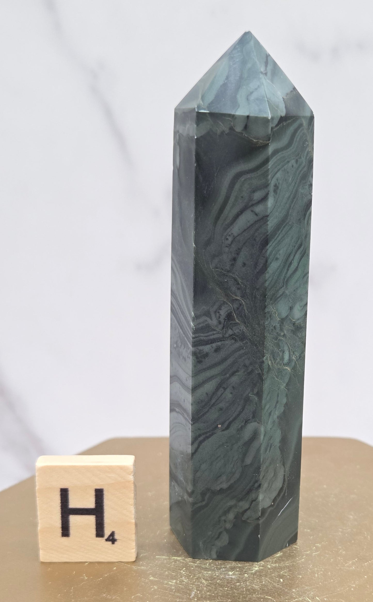 Green wave picture jasper tower on a wood base on a white background
