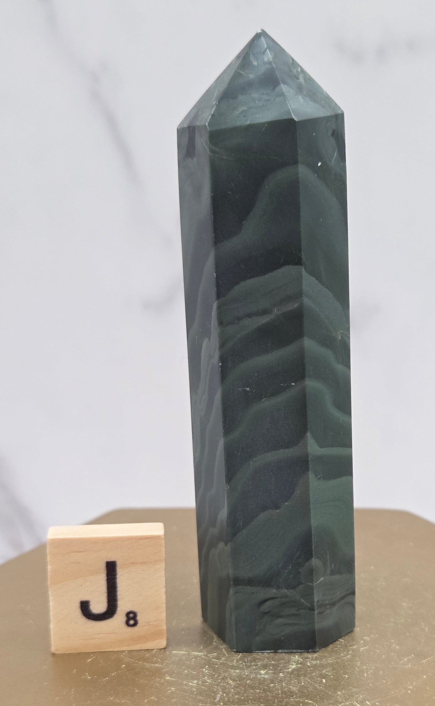 Green wave picture jasper tower on a wood base on a white background