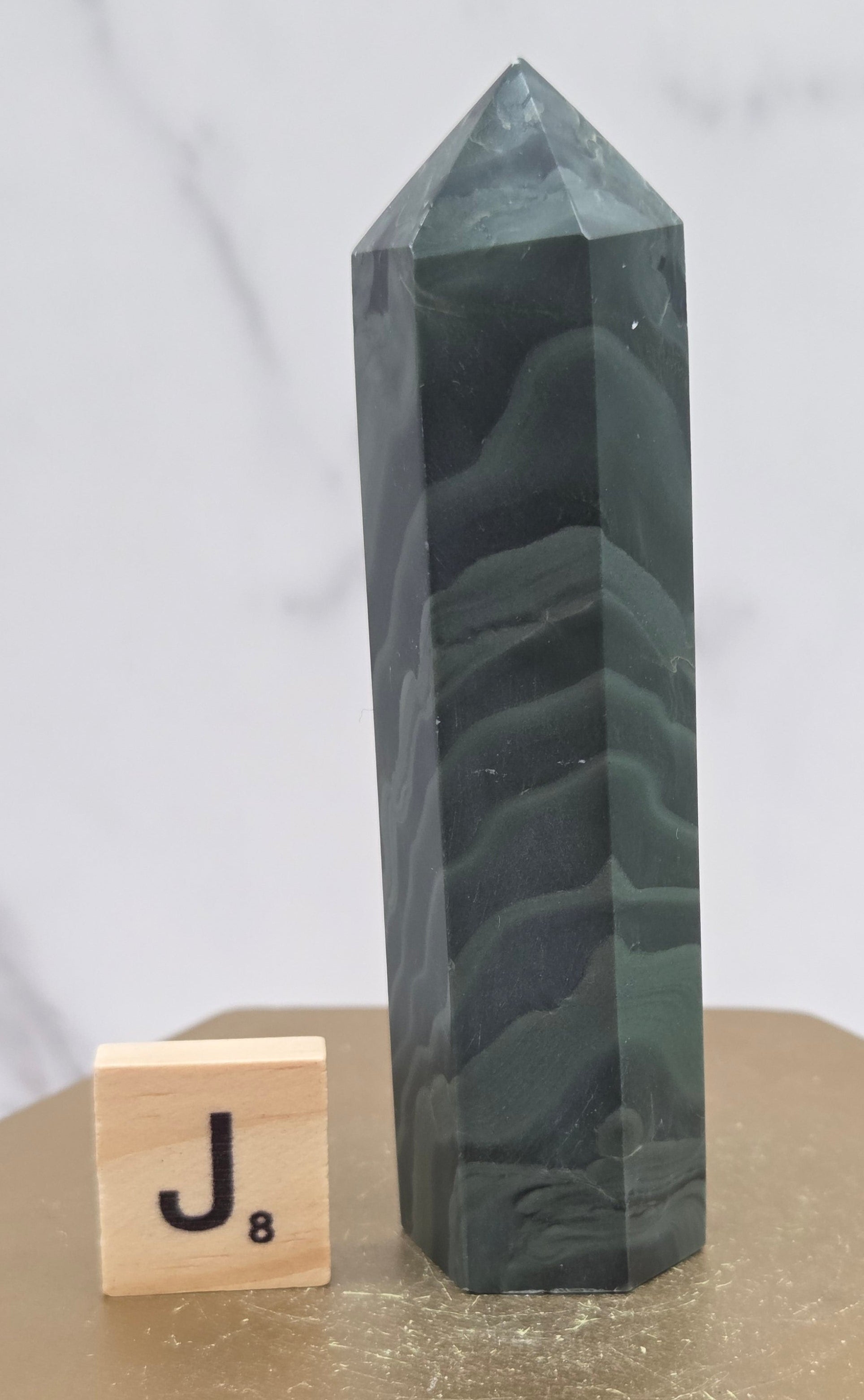 Green wave picture jasper tower on a wood base on a white background