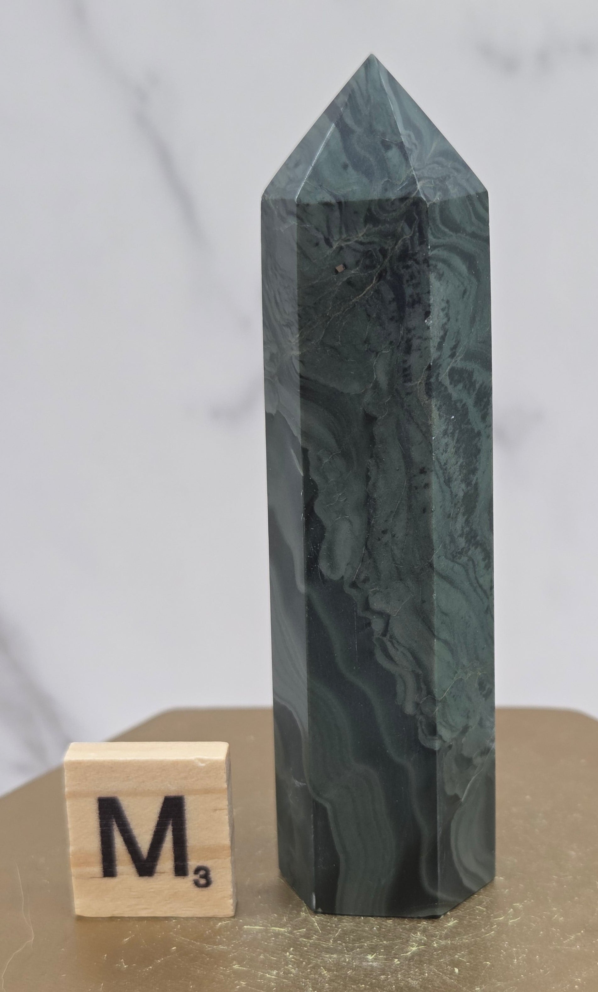 Green wave picture jasper tower on a wood base on a white background