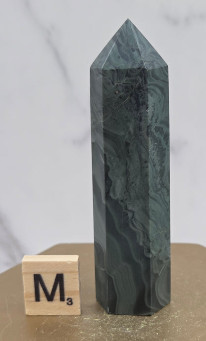 Green wave picture jasper tower on a wood base on a white background