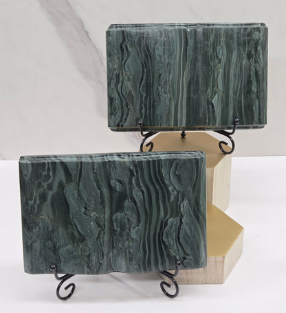 Set of green wave picture jasper carvings made to resemble an open book, on stands, on a white background. Books have wave-like patterns.