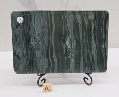 Green wave picture jasper carving made to resemble an open book, on a stand, on a white background. Book has wave-like patterns.