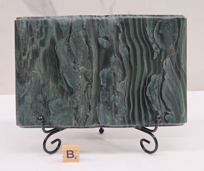 Green wave picture jasper carving made to resemble an open book, on a stand, on a white background. Book has wave-like patterns.
