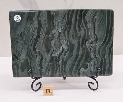 Green wave picture jasper carving made to resemble an open book, on a stand, on a white background. Book has wave-like patterns.