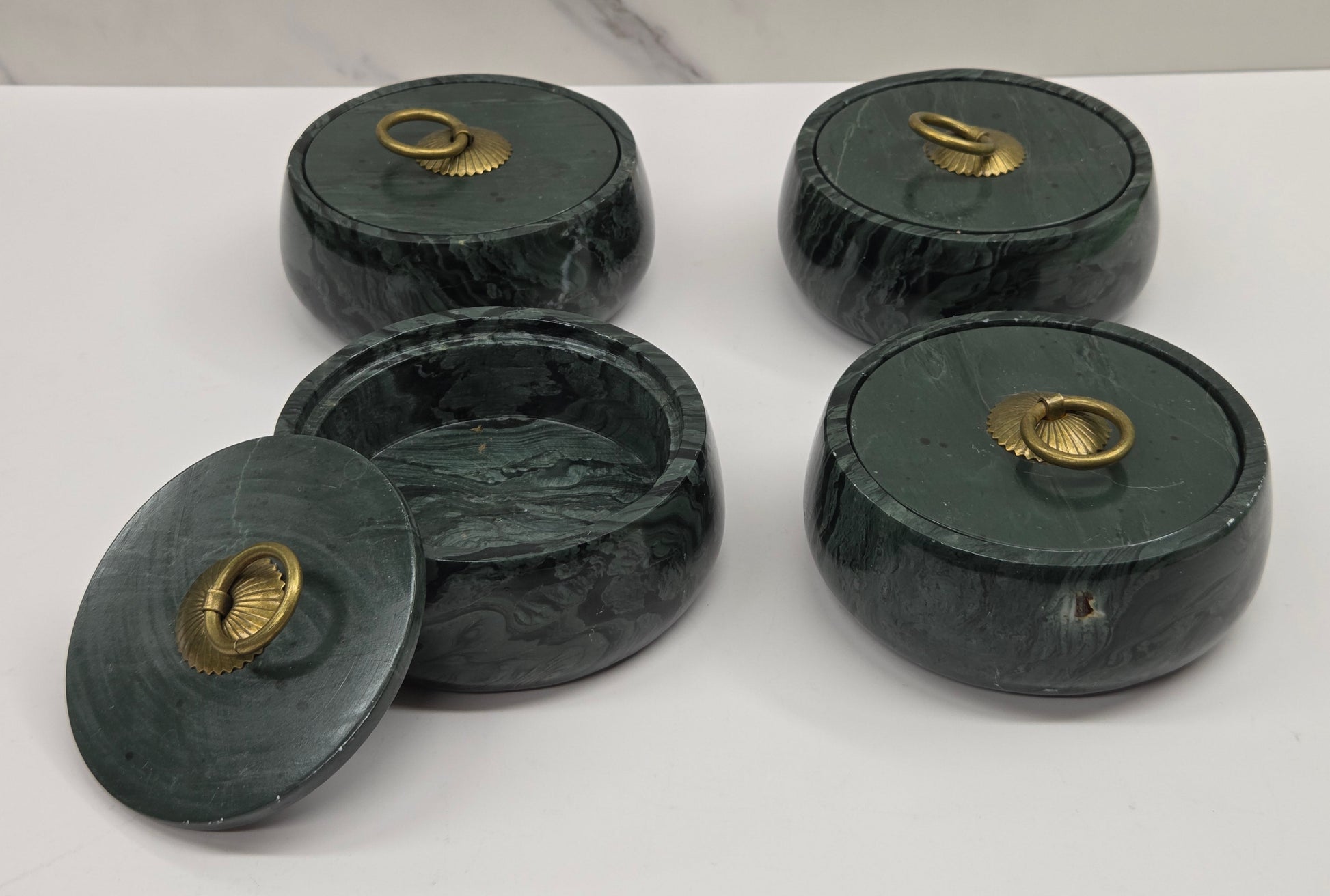 Set of 4 round bowl containers, each  with a gold colored handle on the lid,  made of green wave picture jasper, with wave like patterns, on a white background