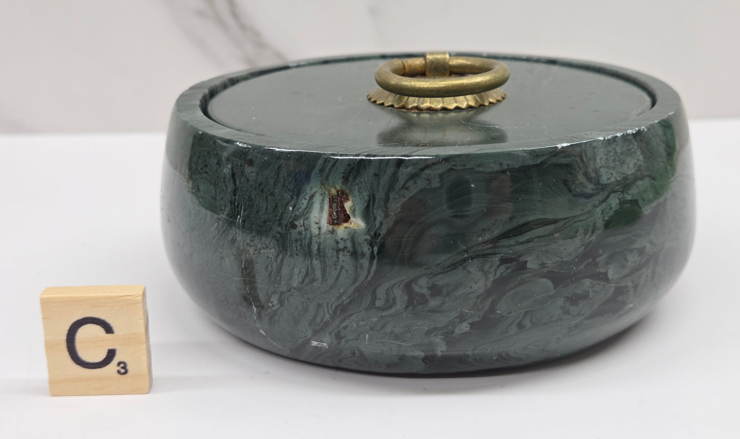 Round bowl container, with a gold colored handle on the lid, made of green wave picture jasper, with wave like patterns, on a white background