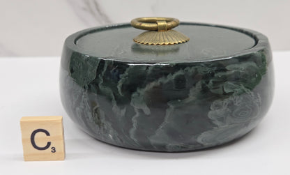 Round bowl container, with a gold colored handle on the lid, made of green wave picture jasper, with wave like patterns, on a white background