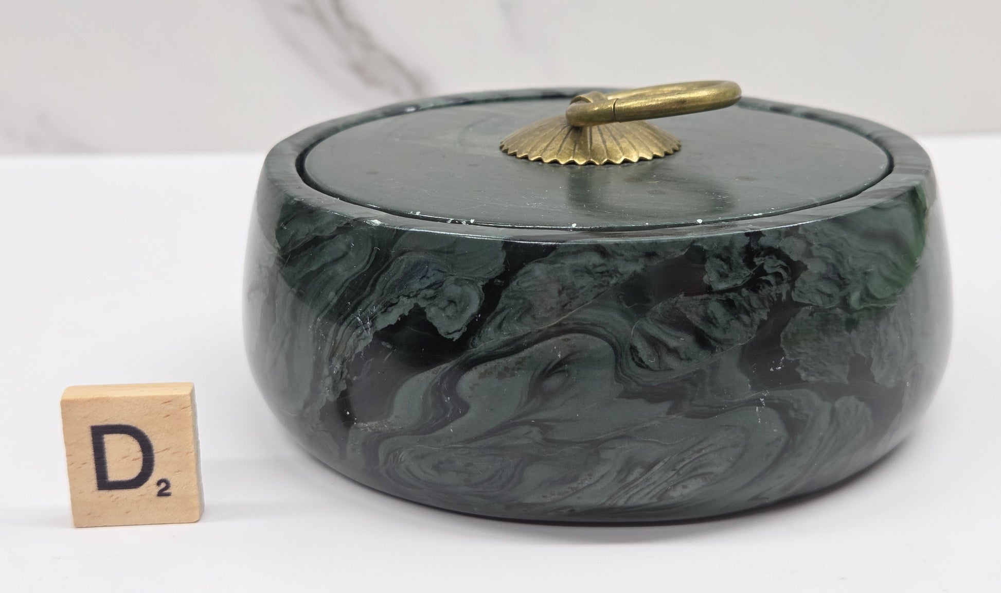 Round bowl container, with a gold colored handle on the lid, made of green wave picture jasper, with wave like patterns, on a white background
