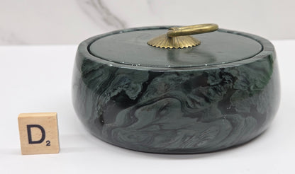 Round bowl container, with a gold colored handle on the lid, made of green wave picture jasper, with wave like patterns, on a white background