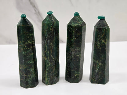 Set of 4 green emerald towers with yellow and black inclusions, on a white background
