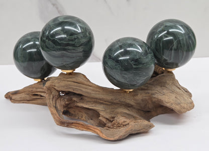 Set of green wave picture jasper spheres with a wave like pattern, on a driftwood stand, on a white background