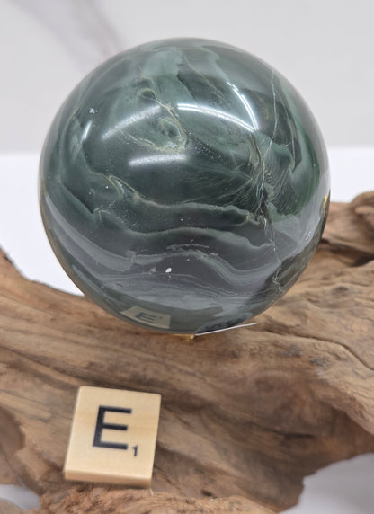 Green wave picture jasper sphere with a wave like pattern, on a driftwood stand, on a white background