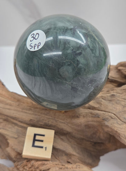 Green wave picture jasper sphere with a wave like pattern, on a driftwood stand, on a white background