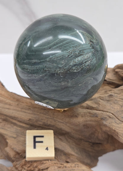 Green wave picture jasper sphere with a wave like pattern, on a driftwood stand, on a white background
