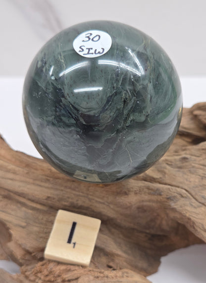 Green wave picture jasper sphere with a wave like pattern, on a driftwood stand, on a white background