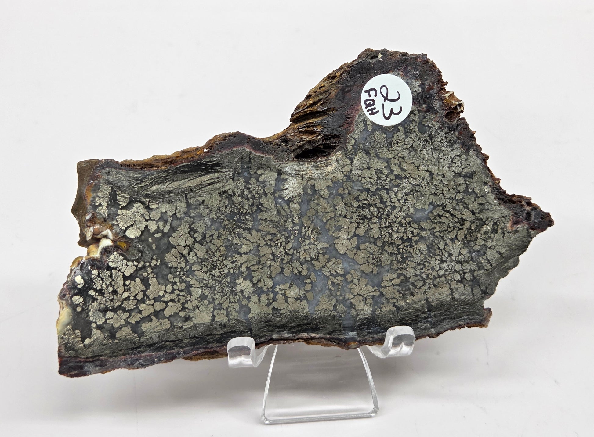 Mineral slab of agate with marcasite on a stand on a white background