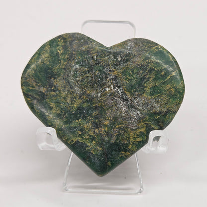 Emerald heart with yellow and black inclusions, on a display stand on a white background
