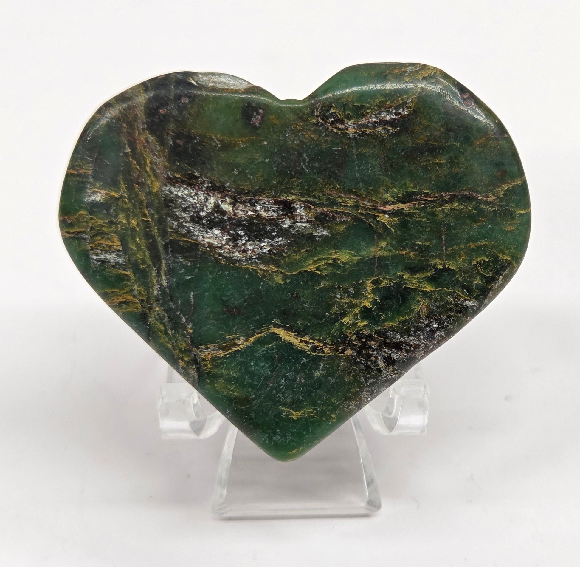 Emerald heart with yellow and black inclusions, on a display stand on a white background