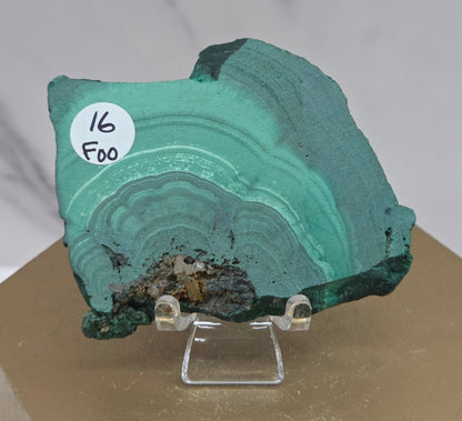 Green mineral specimen on a stand with a label against a neutral background